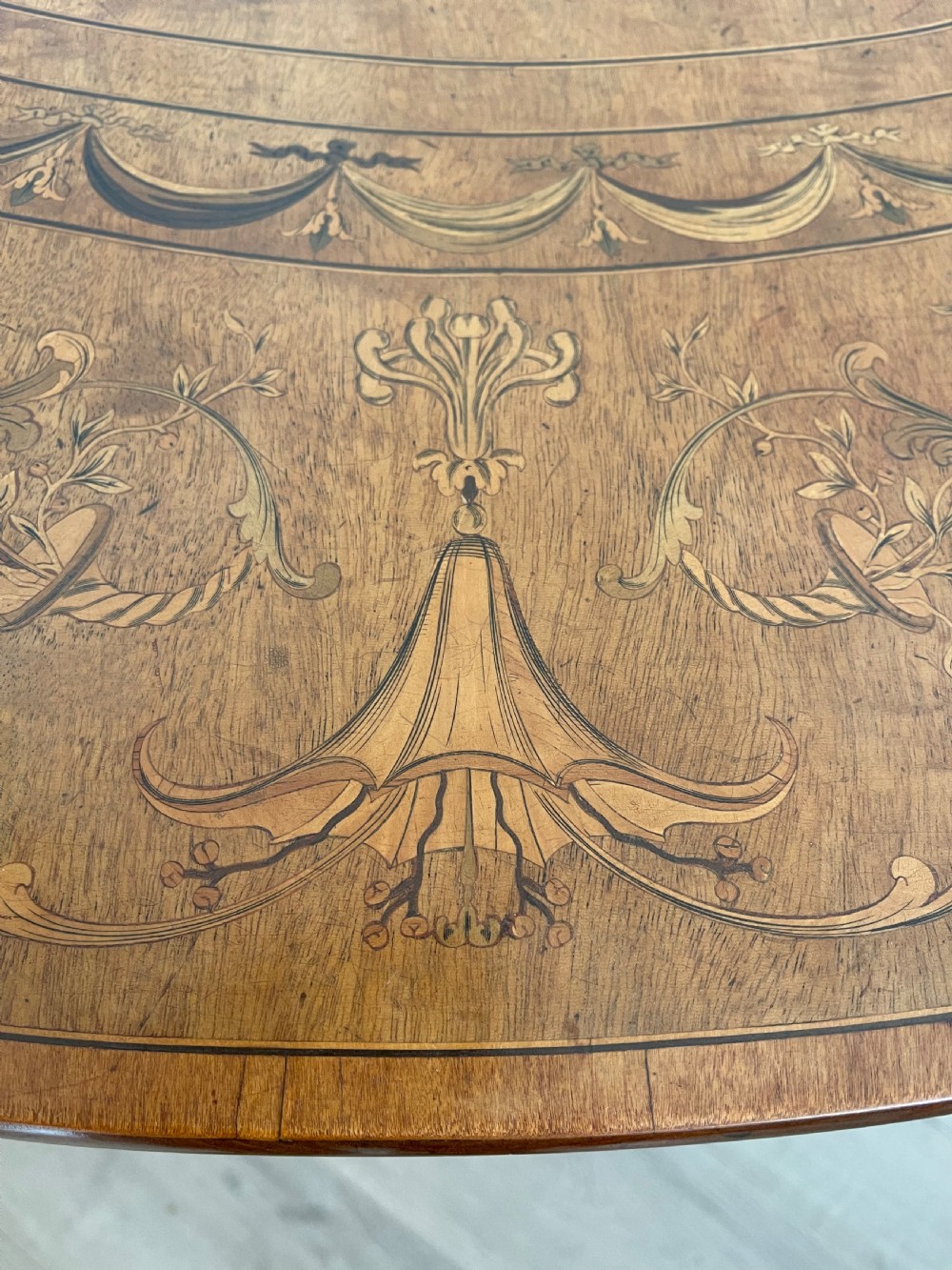 An oval antique mahogany Pembroke table with detailed marquetry inlay, drop leaves, and tapered legs. View XII