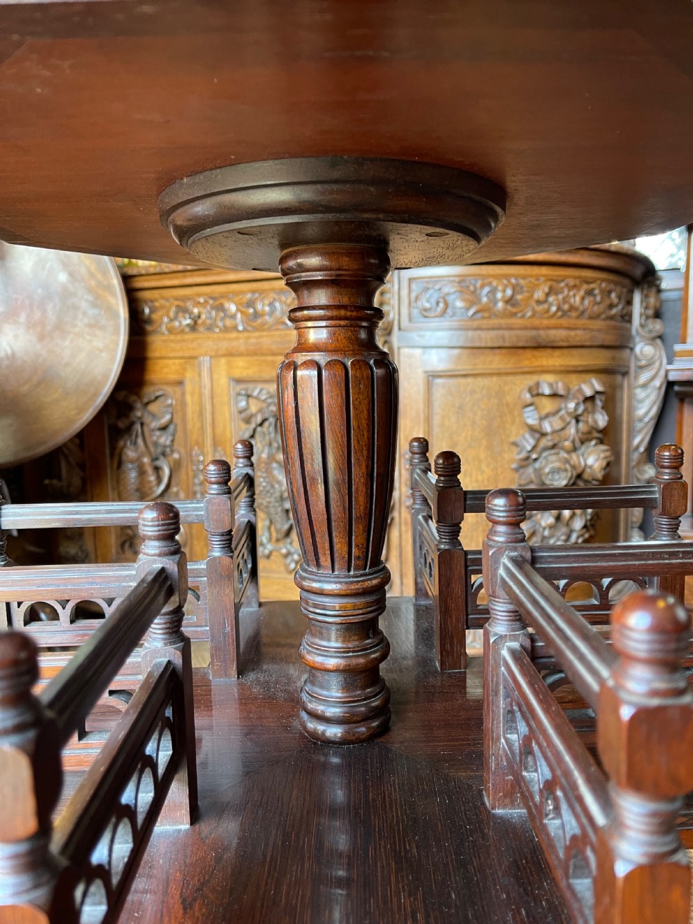 A nineteenth-century rosewood revolving book table featuring an octagonal top, pierced fretwork gallery compartments, turned central column, and four swept legs. View II