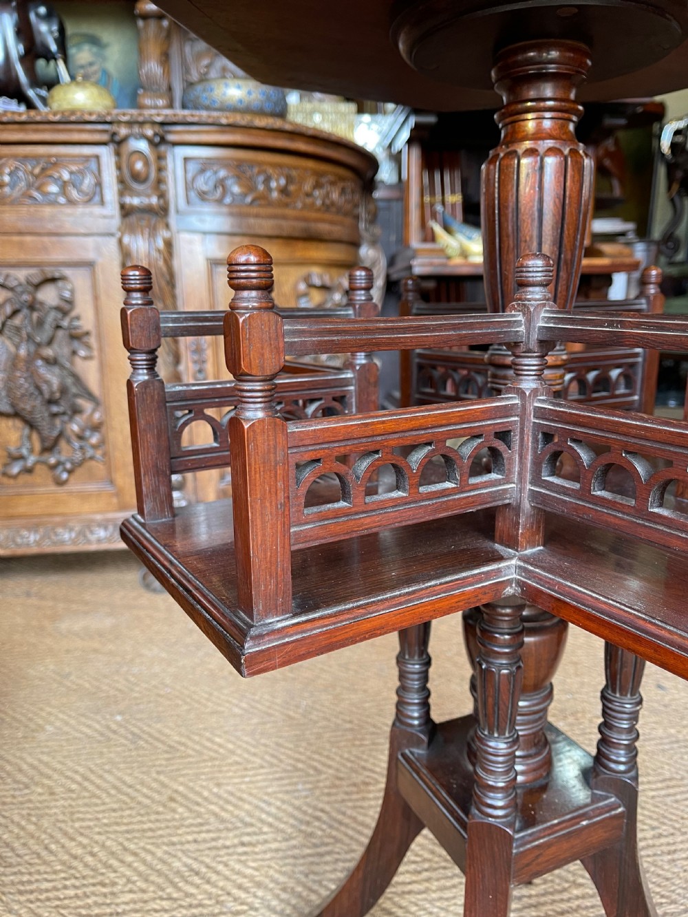 A nineteenth-century rosewood revolving book table featuring an octagonal top, pierced fretwork gallery compartments, turned central column, and four swept legs. View III