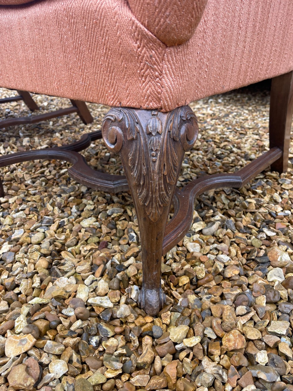 A pair of high-backed armchairs upholstered in textured orange fabric with intricate carved walnut legs and serpentine stretchers. View II