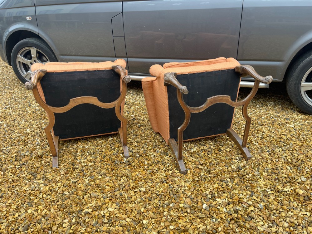 A pair of high-backed armchairs upholstered in textured orange fabric with intricate carved walnut legs and serpentine stretchers. View V