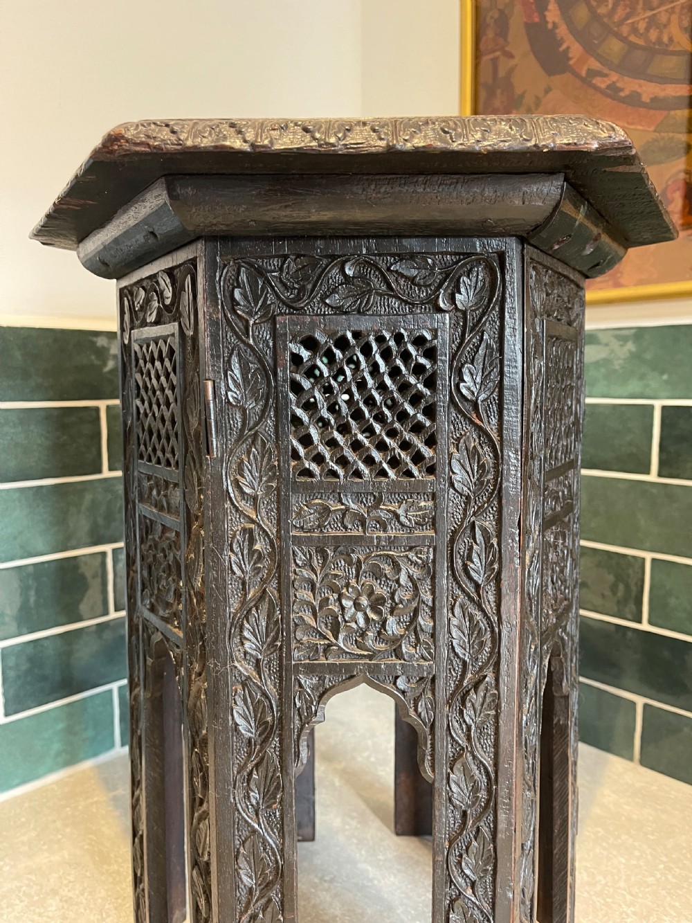 An octagonal dark wood side table with intricate hand-carved foliate patterns and openwork lattice panels on the base. View III