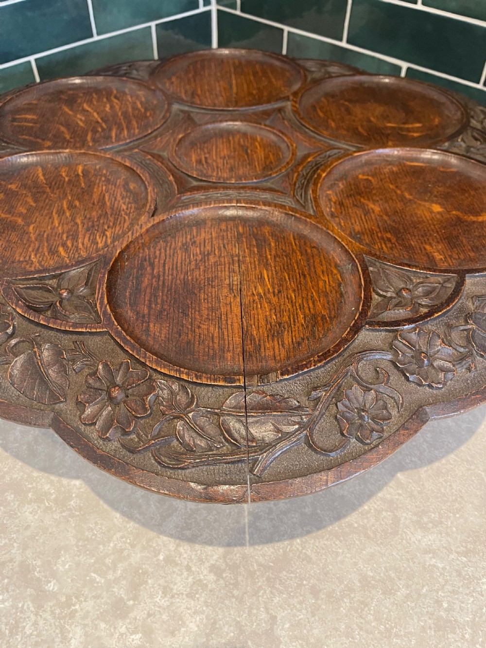 A circular carved oak Lazy Susan featuring six outer recessed circular compartments, one central compartment, and a floral carved scalloped border. View III