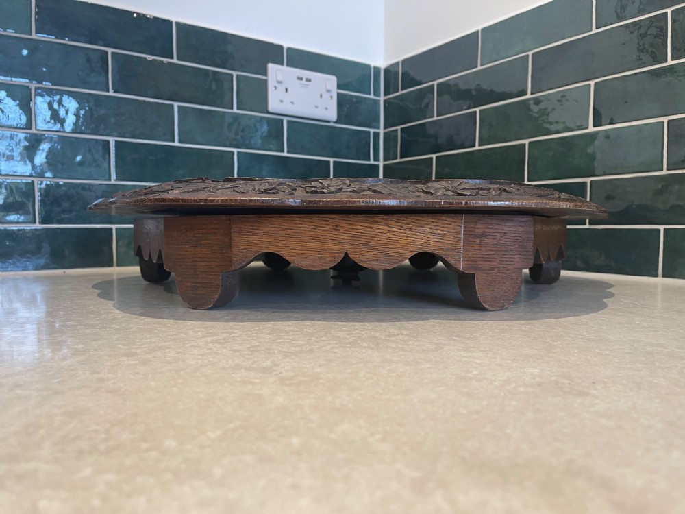 A circular carved oak Lazy Susan featuring six outer recessed circular compartments, one central compartment, and a floral carved scalloped border. View VI