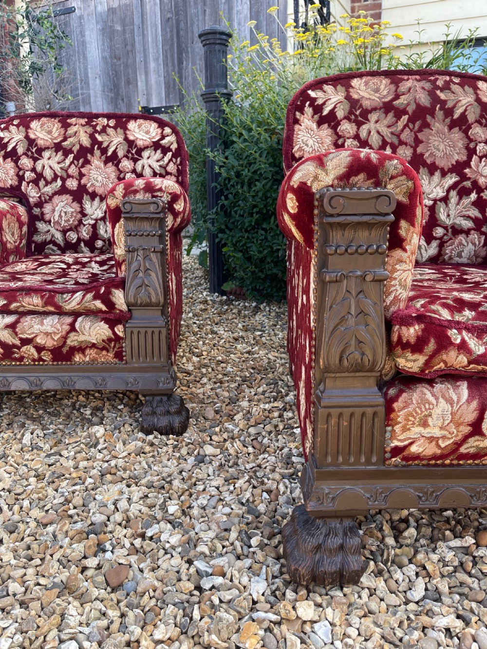 A pair of low-slung, deep-seated armchairs upholstered in burgundy and gold floral velvet with carved oak facings and claw feet. View II