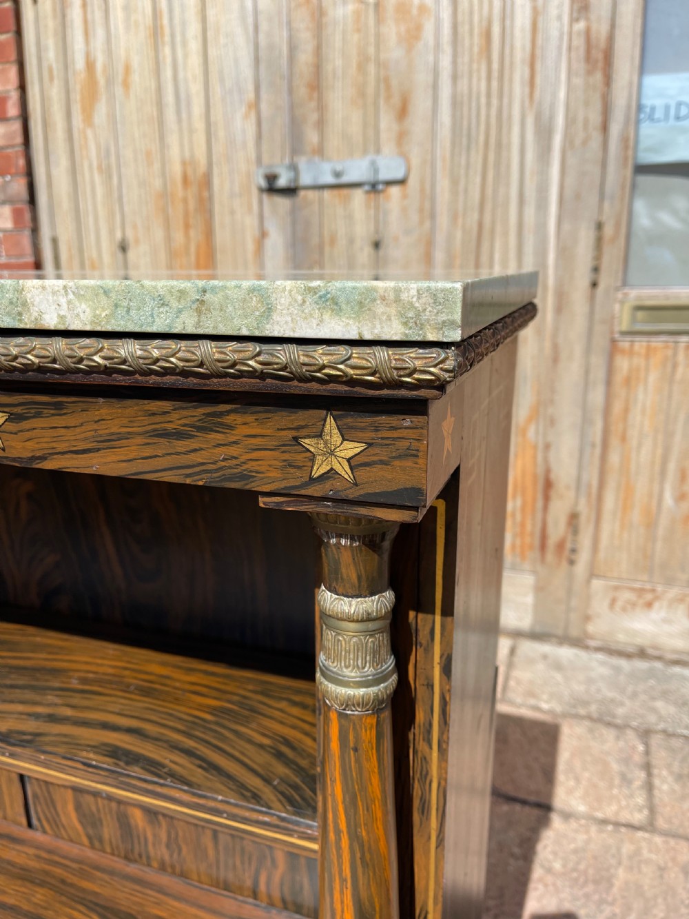 An early nineteenth-century open bookcase featuring a simulated rosewood painted finish, green marble top, gilt star motifs, and turned side columns. View II