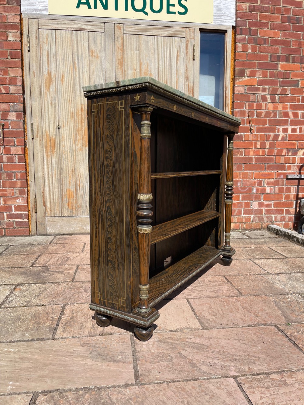 An early nineteenth-century open bookcase featuring a simulated rosewood painted finish, green marble top, gilt star motifs, and turned side columns. View VII