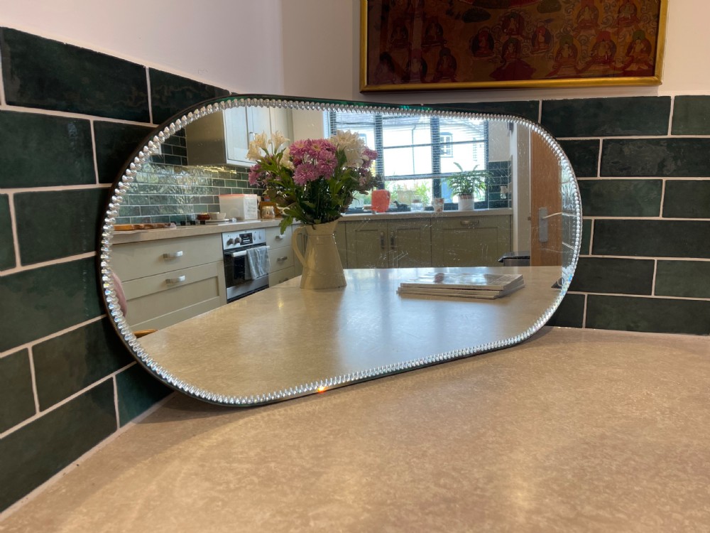 An oblong mirrored plateau tray featuring a decorative clear beaded glass border designed to lie flat on a surface.