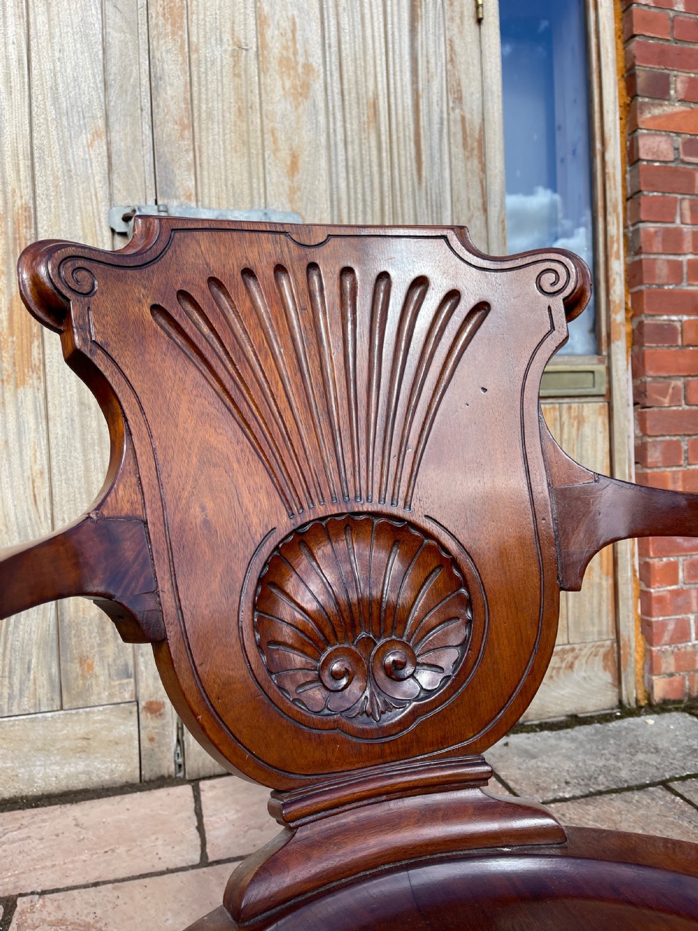 A late nineteenth-century carved mahogany revolving desk chair featuring a shell-carved backrest, curved armrests, a contoured wooden seat, and cabriole legs. View II