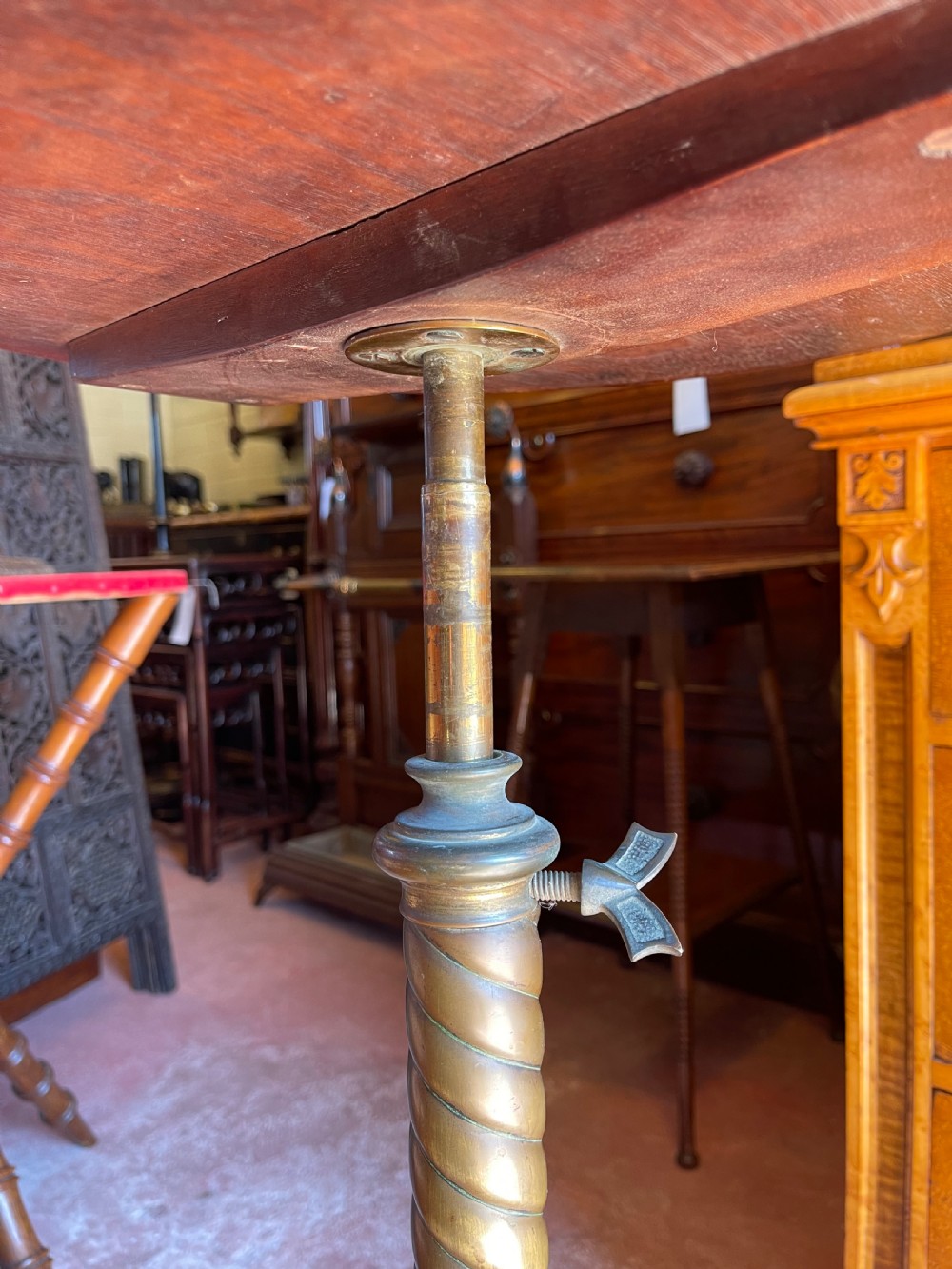 A nineteenth-century height-adjustable stand featuring a circular mahogany tabletop, a spiralled column with a wing nut mechanism, and an ornate cast metal base with castors. View IV