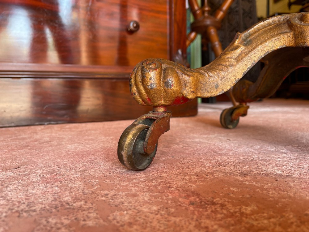 A nineteenth-century height-adjustable stand featuring a circular mahogany tabletop, a spiralled column with a wing nut mechanism, and an ornate cast metal base with castors. View V