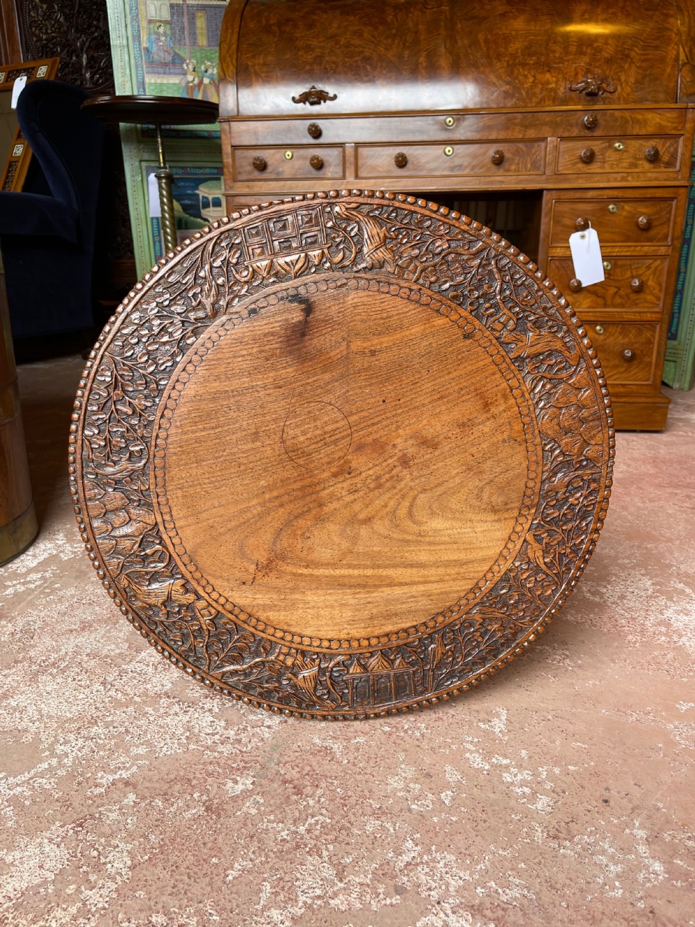 A round wooden pedestal table featuring hand-carved foliate borders and a sculpted tripod base. View II