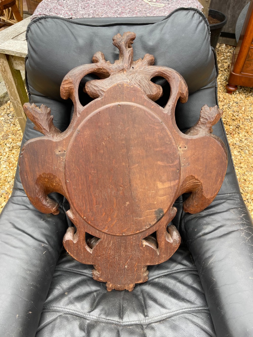 A nineteenth-century carved oak wall mirror featuring an oval glass plate framed by ornate scrollwork, acanthus leaves, and a carved face at the base. View VI
