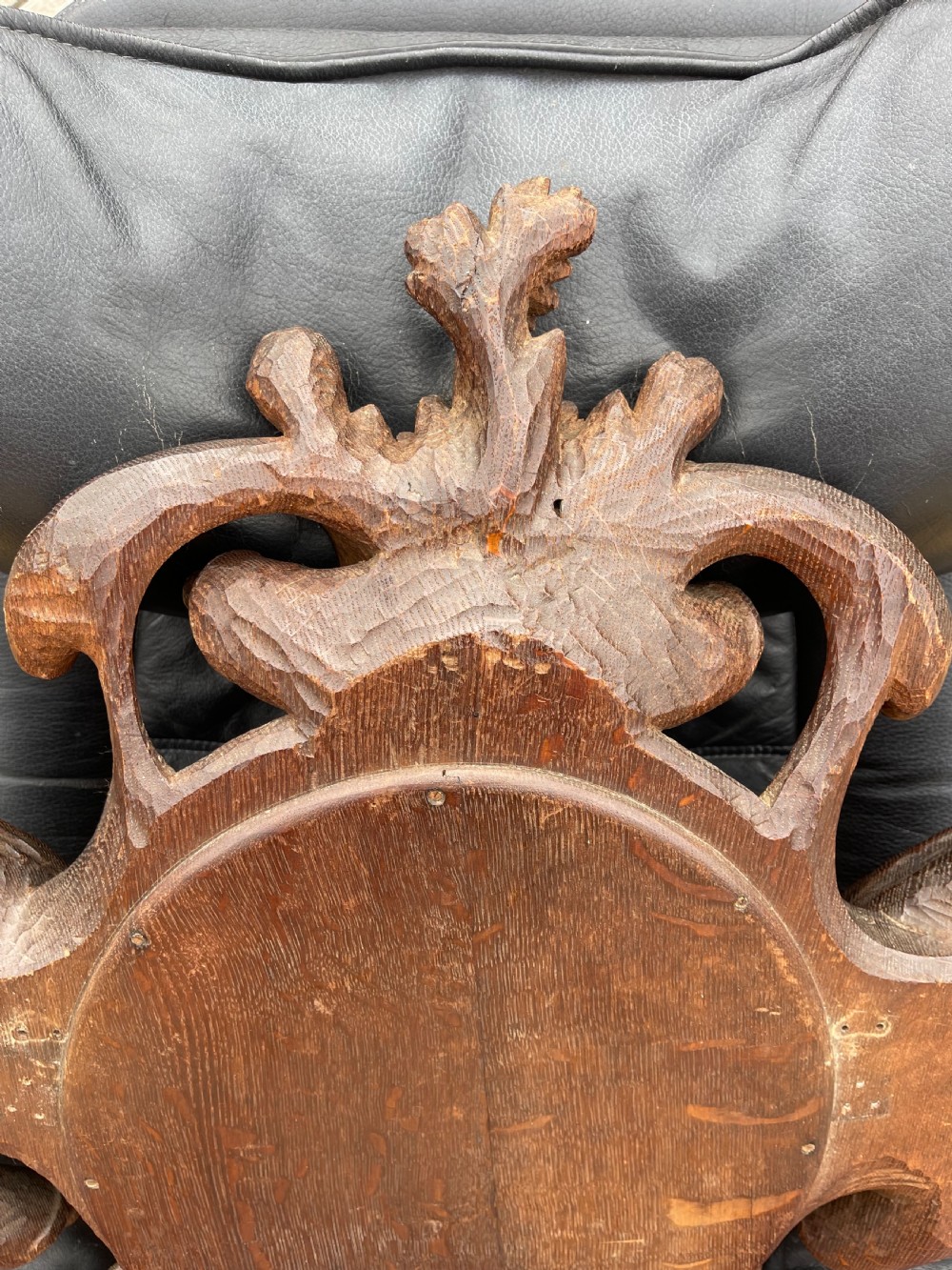 A nineteenth-century carved oak wall mirror featuring an oval glass plate framed by ornate scrollwork, acanthus leaves, and a carved face at the base. View VII