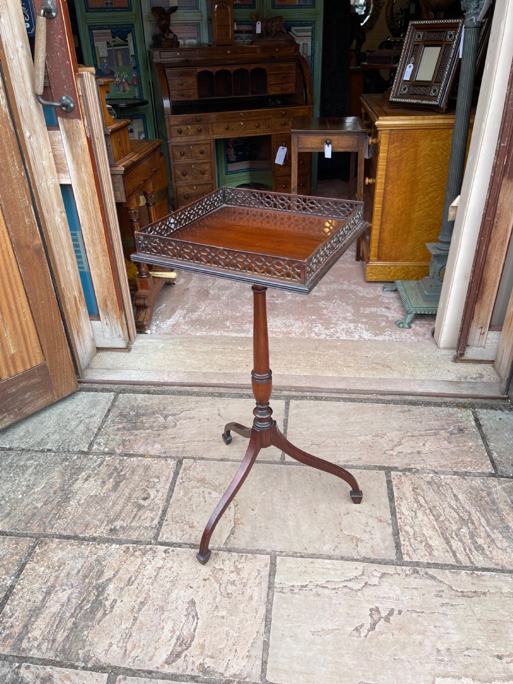 A tall mahogany pedestal side table featuring a square top with a fretwork gallery, a turned stem, and three splayed legs.