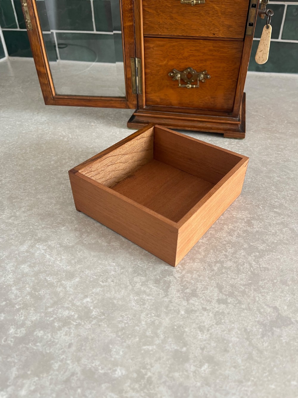 A 19th-century oak tabletop cabinet featuring three internal drawers behind an arched glazed door with decorative brass drop handles. View VIII
