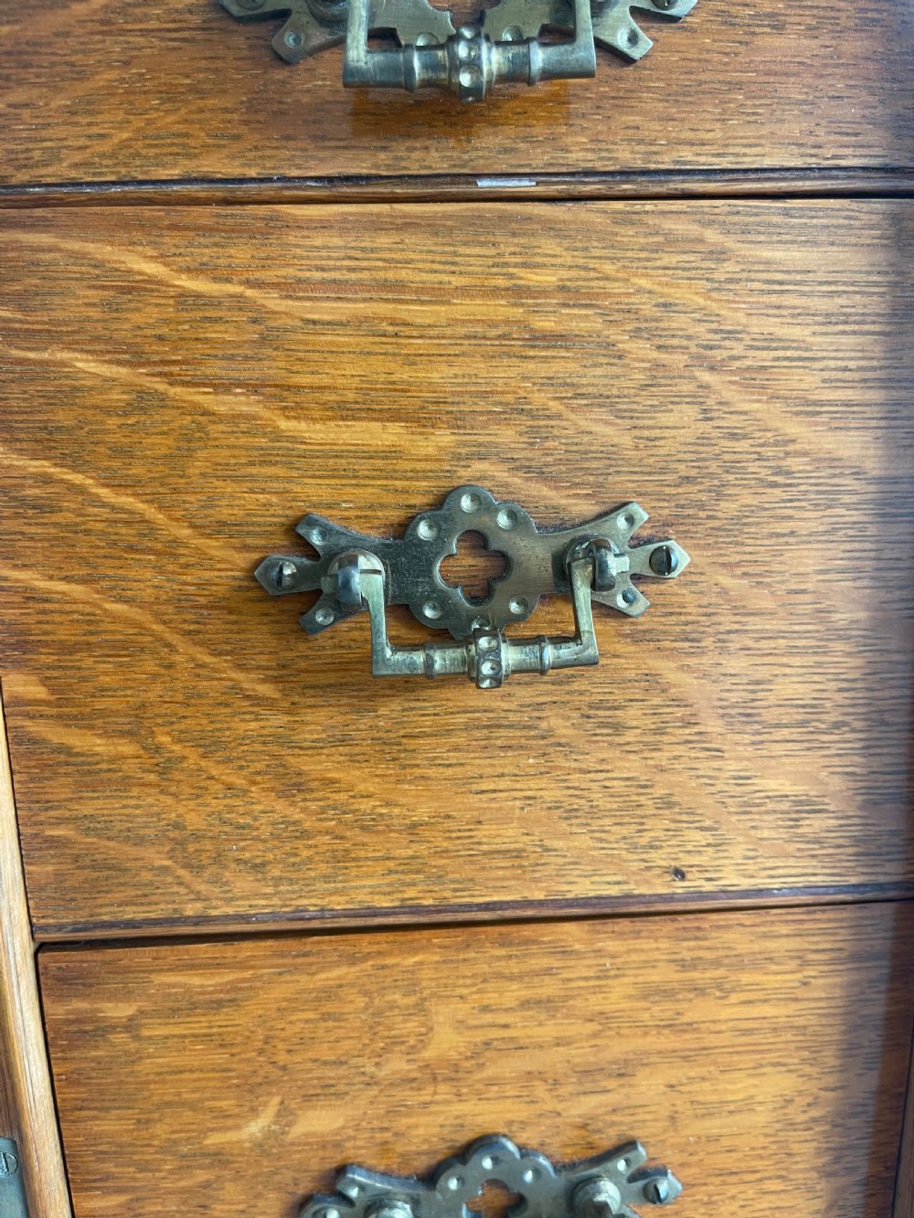A 19th-century oak tabletop cabinet featuring three internal drawers behind an arched glazed door with decorative brass drop handles. View IX