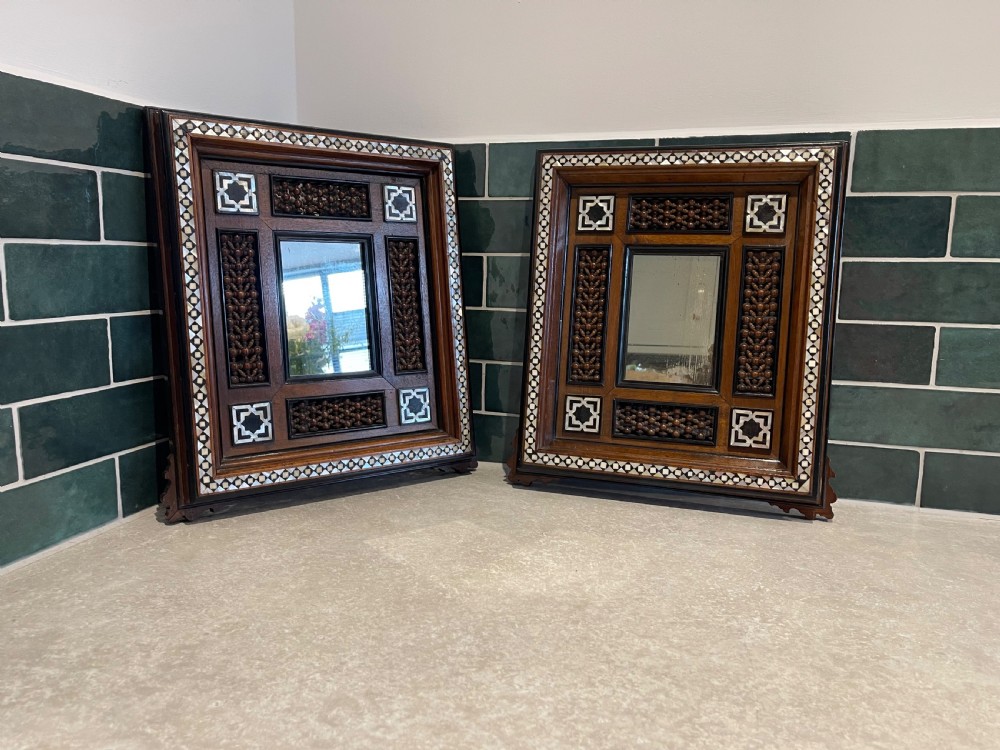 A matching pair of dark walnut wall mirrors featuring intricate mother-of-pearl inlay and decorative turned wood lattice panels framing central rectangular mirrors.