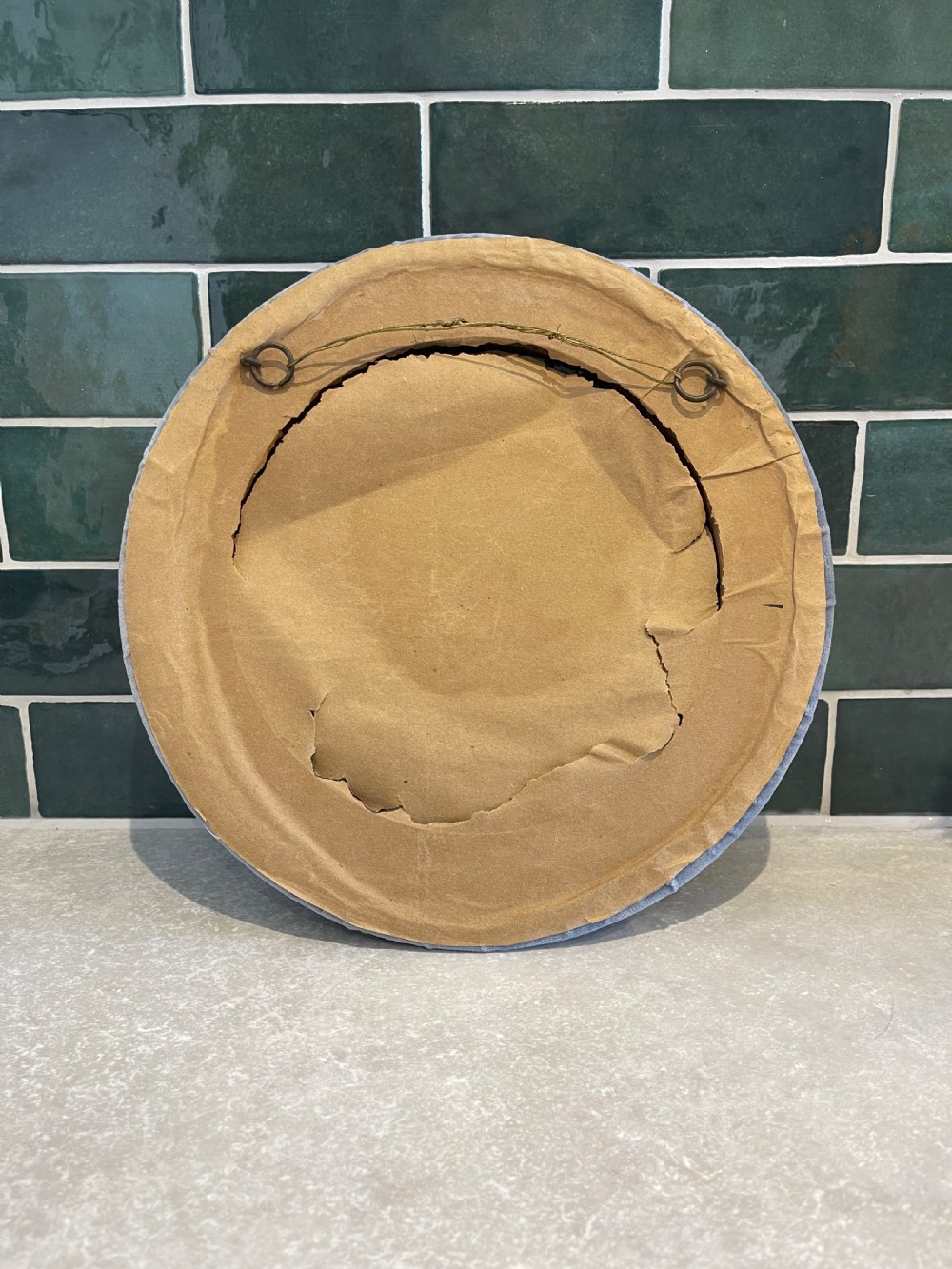 A circular convex sorcerer wall mirror featuring a padded grey velvet outer frame and an inner border of glass cabochons. View III