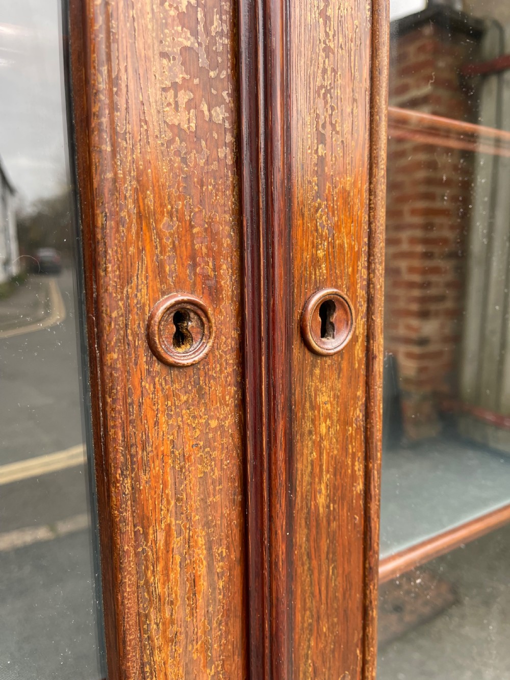 A tall dark rosewood Continental display cabinet featuring arched glazed double doors, an intricate carved pediment cresting, and a lower drawer. View II
