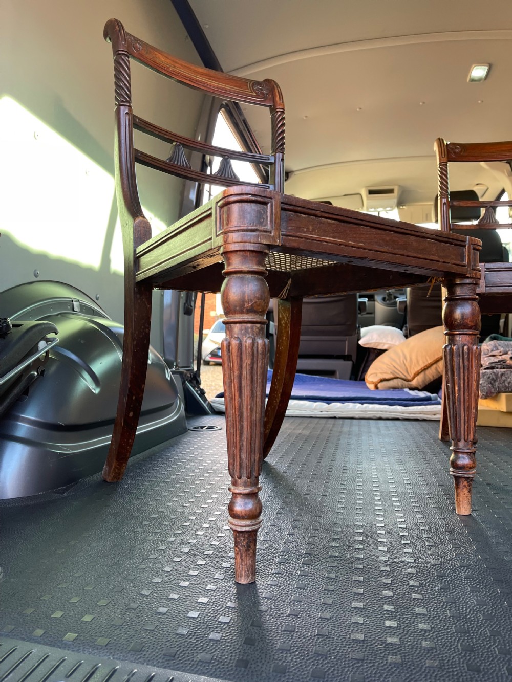 A pair of antique Regency style dark mahogany side chairs featuring carved top rails, woven cane seats, and reeded front legs. View II