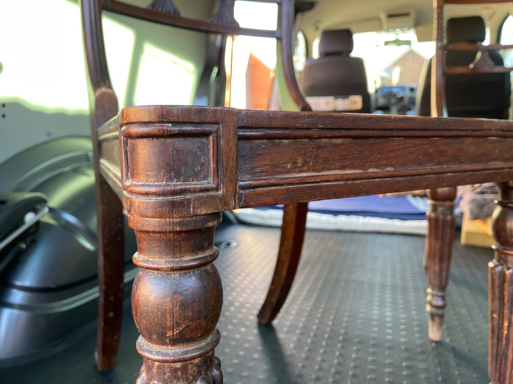 A pair of antique Regency style dark mahogany side chairs featuring carved top rails, woven cane seats, and reeded front legs. View III