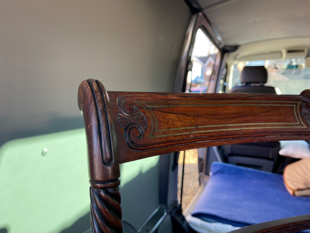 A pair of antique Regency style dark mahogany side chairs featuring carved top rails, woven cane seats, and reeded front legs. View VI