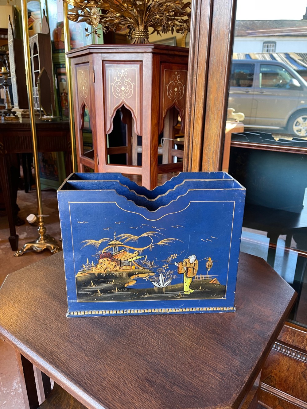A blue painted wooden stationery desk tidy decorated with hand-painted gilt Chinoiserie scenes featuring figures and pagodas, with shaped internal letter dividers.