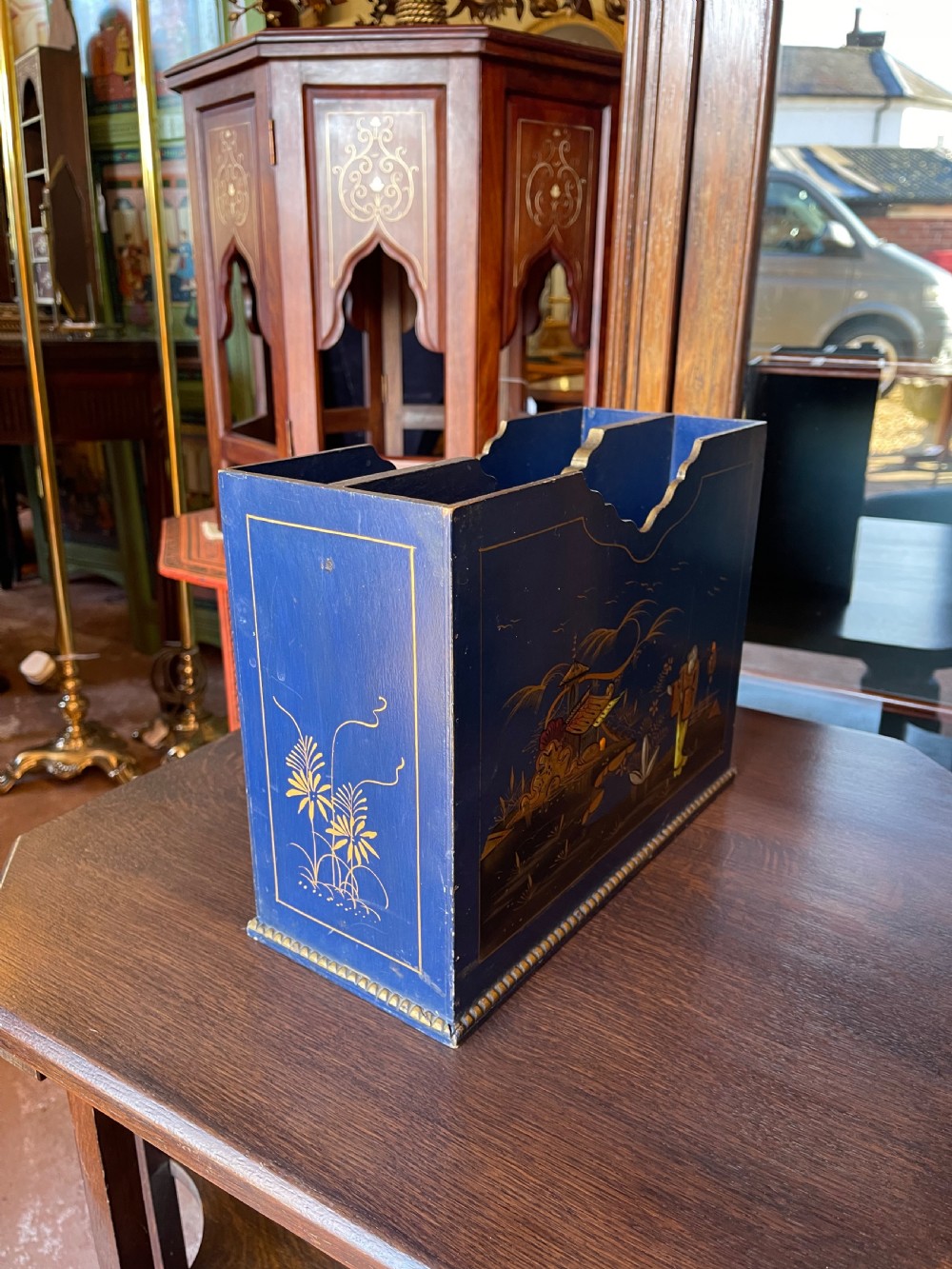 A blue painted wooden stationery desk tidy decorated with hand-painted gilt Chinoiserie scenes featuring figures and pagodas, with shaped internal letter dividers. View II