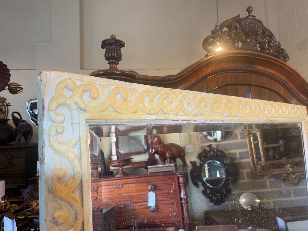 A large rectangular wall mirror featuring a cream-painted wooden frame decorated with a continuous carved Vitruvian scroll wave motif along all four sides. View III