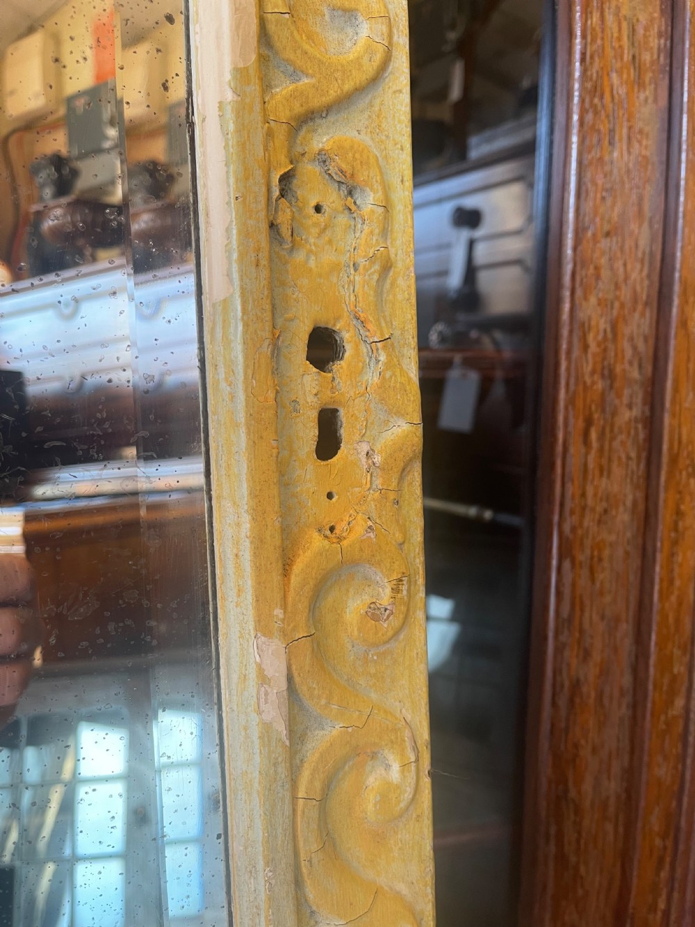 A large rectangular wall mirror featuring a cream-painted wooden frame decorated with a continuous carved Vitruvian scroll wave motif along all four sides. View IV