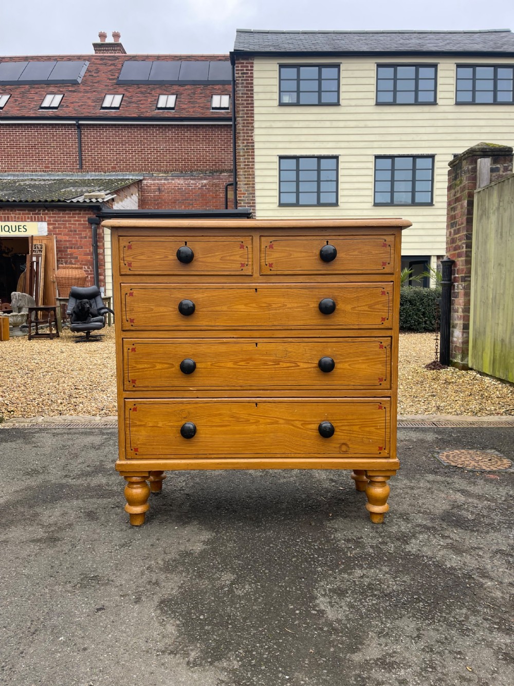 Victorian honey pine chest of drawers featuring two short drawers over three long drawers with dark turned knobs and painted decorative corner accents.