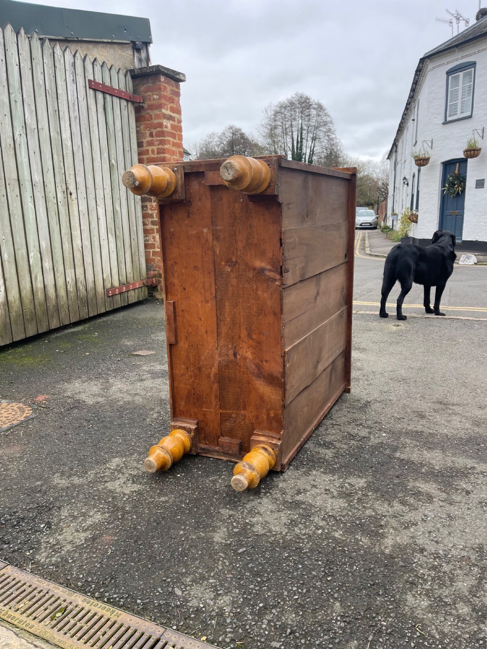 Victorian honey pine chest of drawers featuring two short drawers over three long drawers with dark turned knobs and painted decorative corner accents. View VII