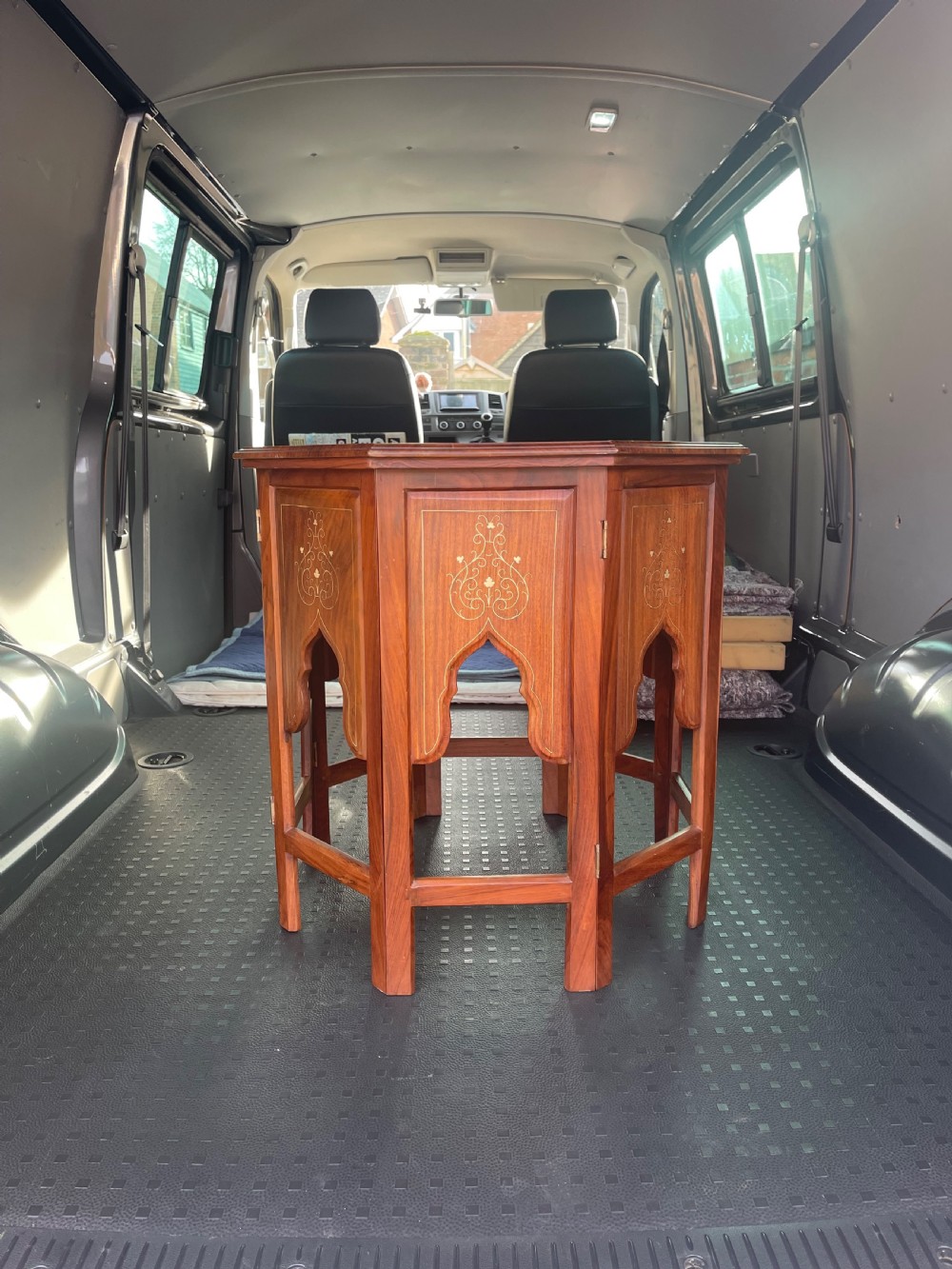 An octagonal warm brown wooden side table with delicate brass wire inlays and pointed arch cut-outs around the base.