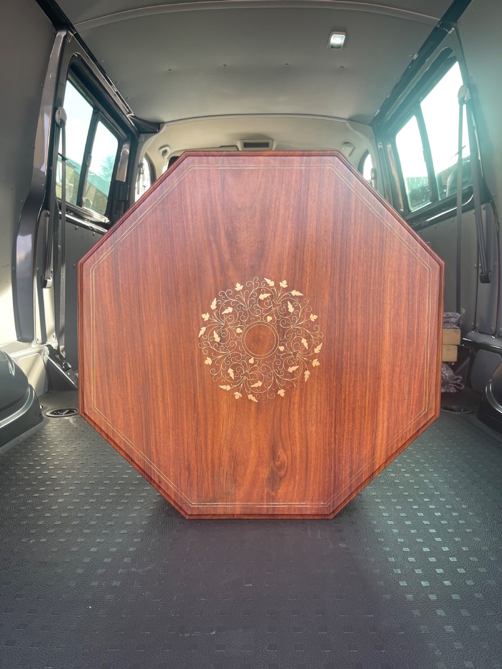 An octagonal warm brown wooden side table with delicate brass wire inlays and pointed arch cut-outs around the base. View II