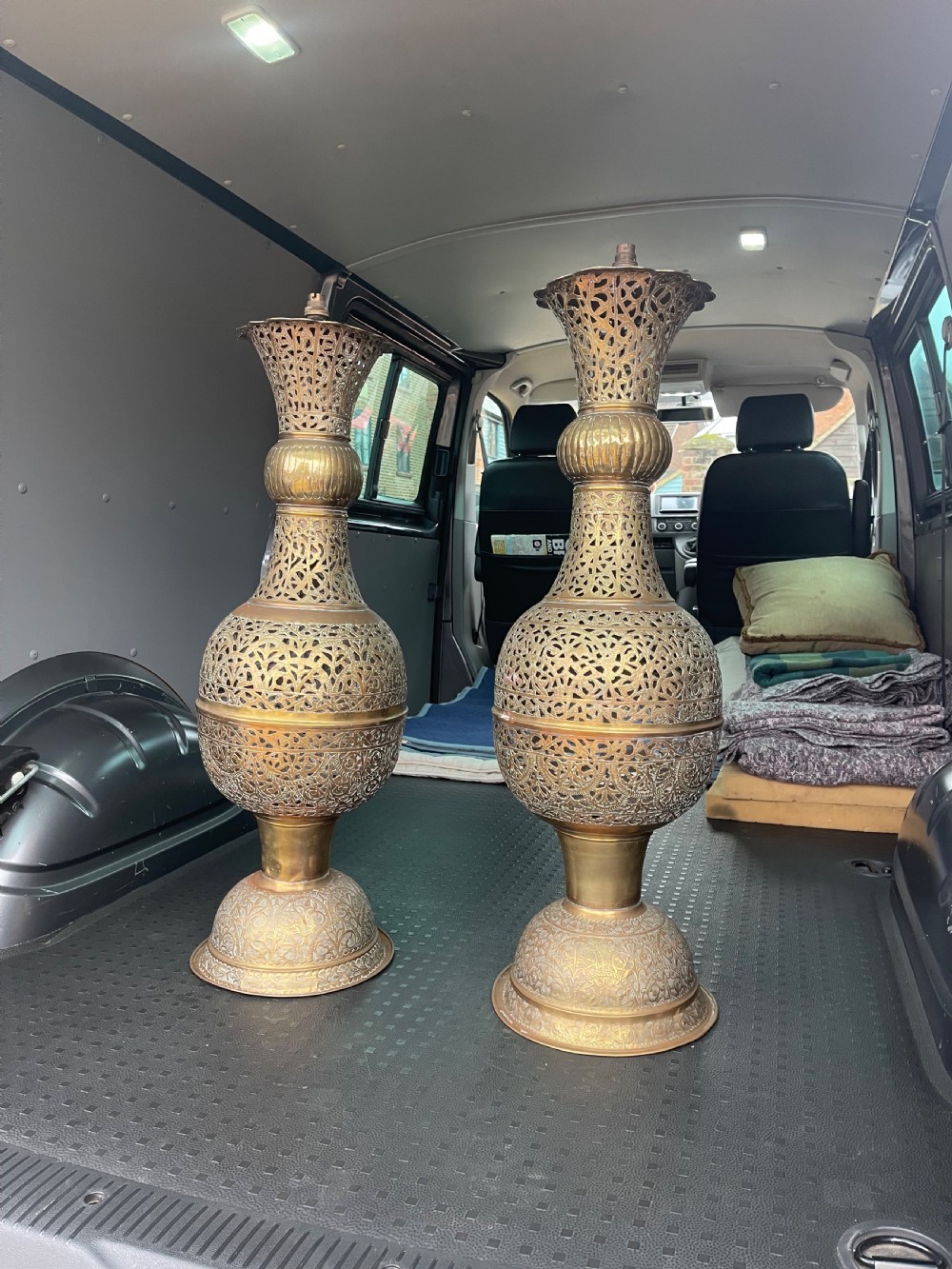 A pair of large antique brass Cairoware lamps featuring intricate pierced arabesque metalwork and tiered urn-shaped bodies.
