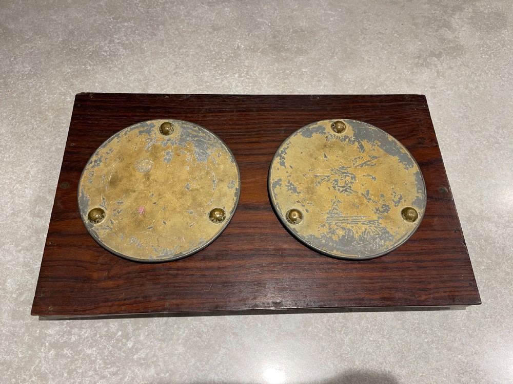 A pair of circular sorcerer-style glass plateau mirrors featuring raised cabochon borders resting on a dark wood panel. View II