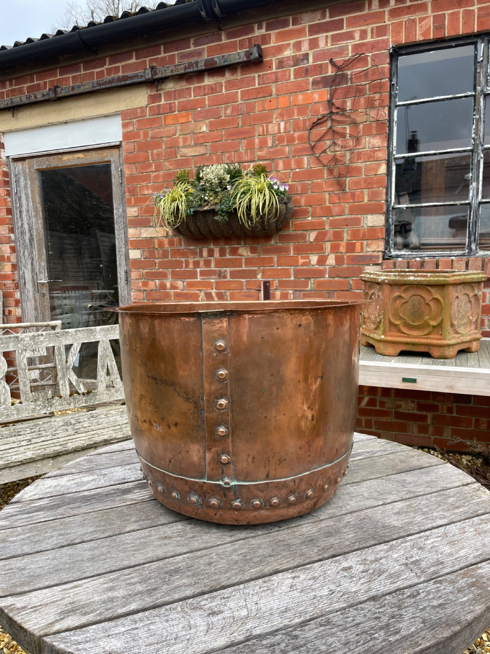 A large nineteenth-century cylindrical copper tub featuring heavy riveted vertical seams and a natural weathered patina.