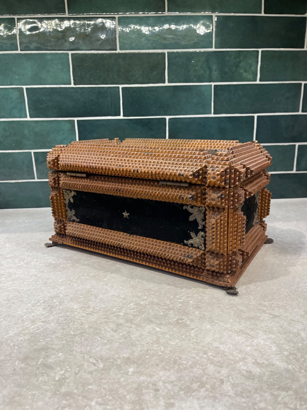 An antique tramp art box featuring layered notch-carved brown wood, dark velvet panels, metal corner mounts, and claw feet. View III