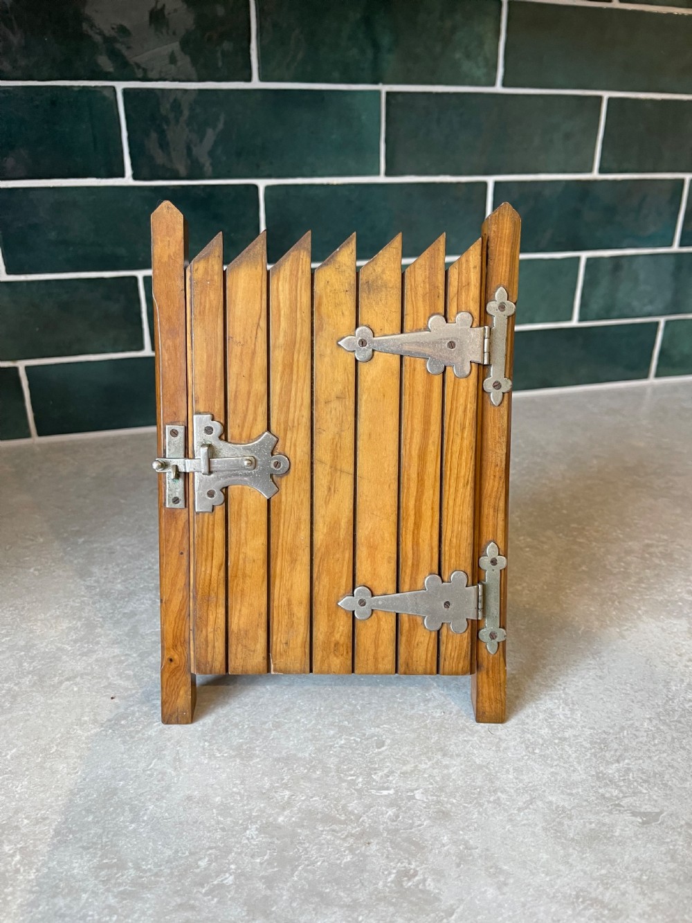 A standing wooden double photo frame constructed in the form of a slatted garden gate with metal strap hinges and a sliding latch.