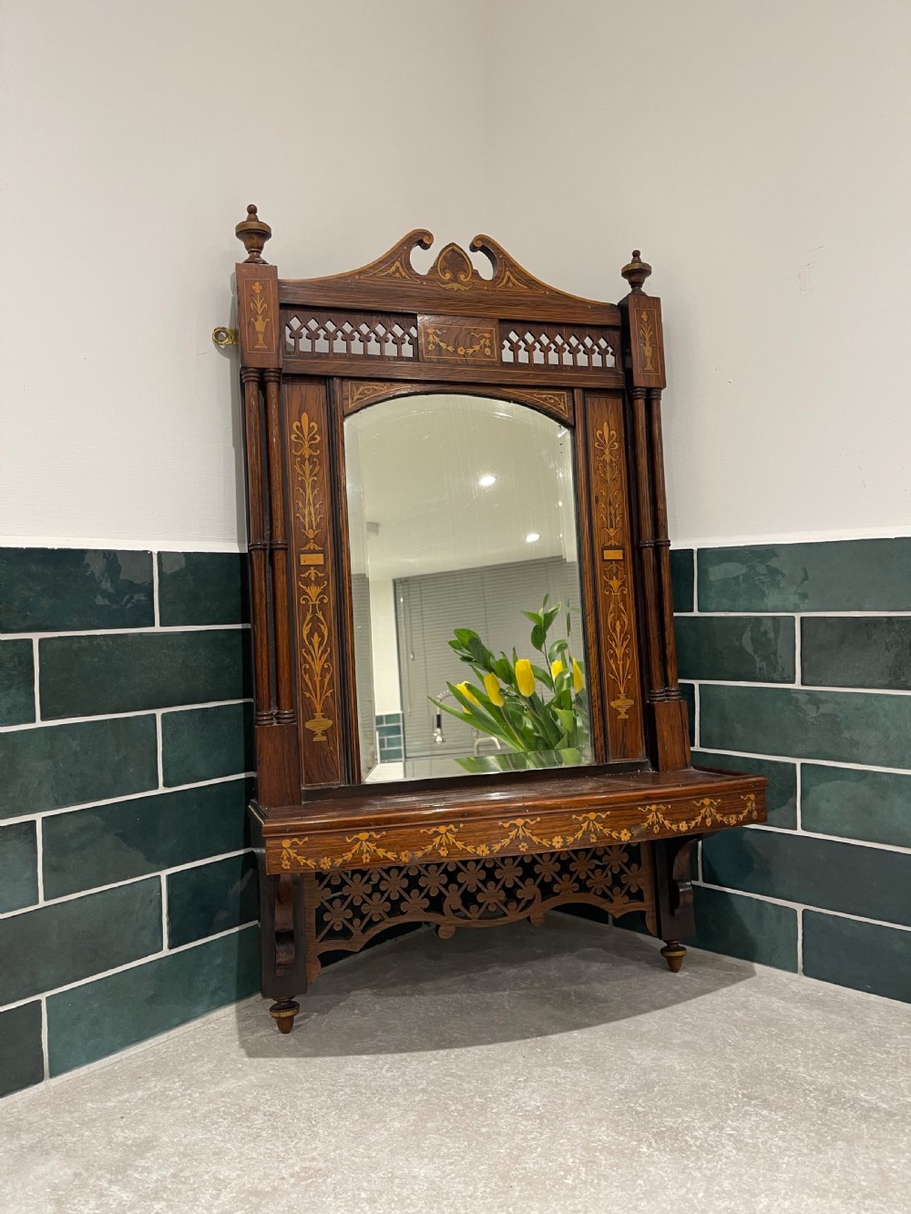 A late Victorian dark wood wall shelf featuring marquetry floral inlay, turned side columns, an arched central mirror, and a pierced fretwork apron.