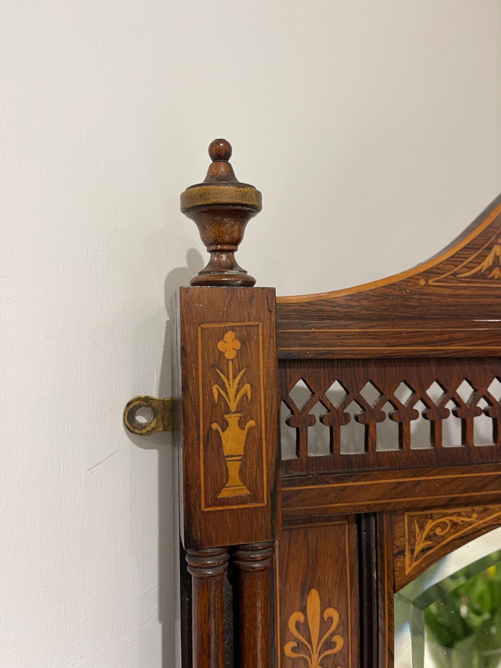 A late Victorian dark wood wall shelf featuring marquetry floral inlay, turned side columns, an arched central mirror, and a pierced fretwork apron. View IV