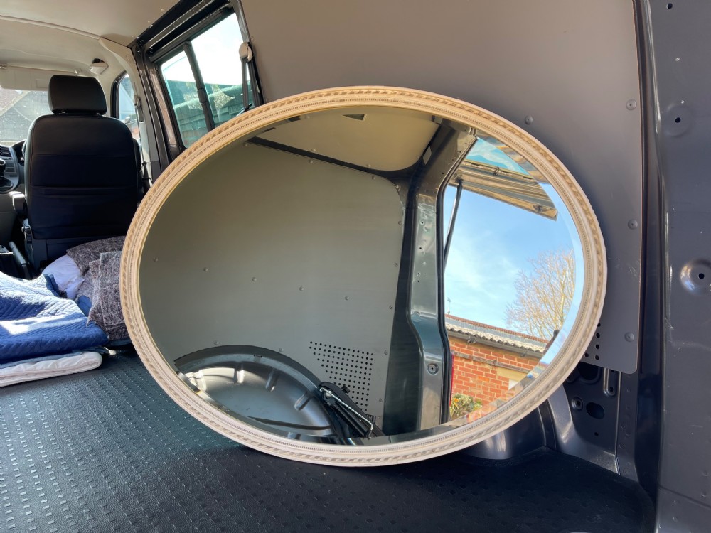 A large Edwardian oval wall mirror featuring a painted off-white frame decorated with a beaded border trim.