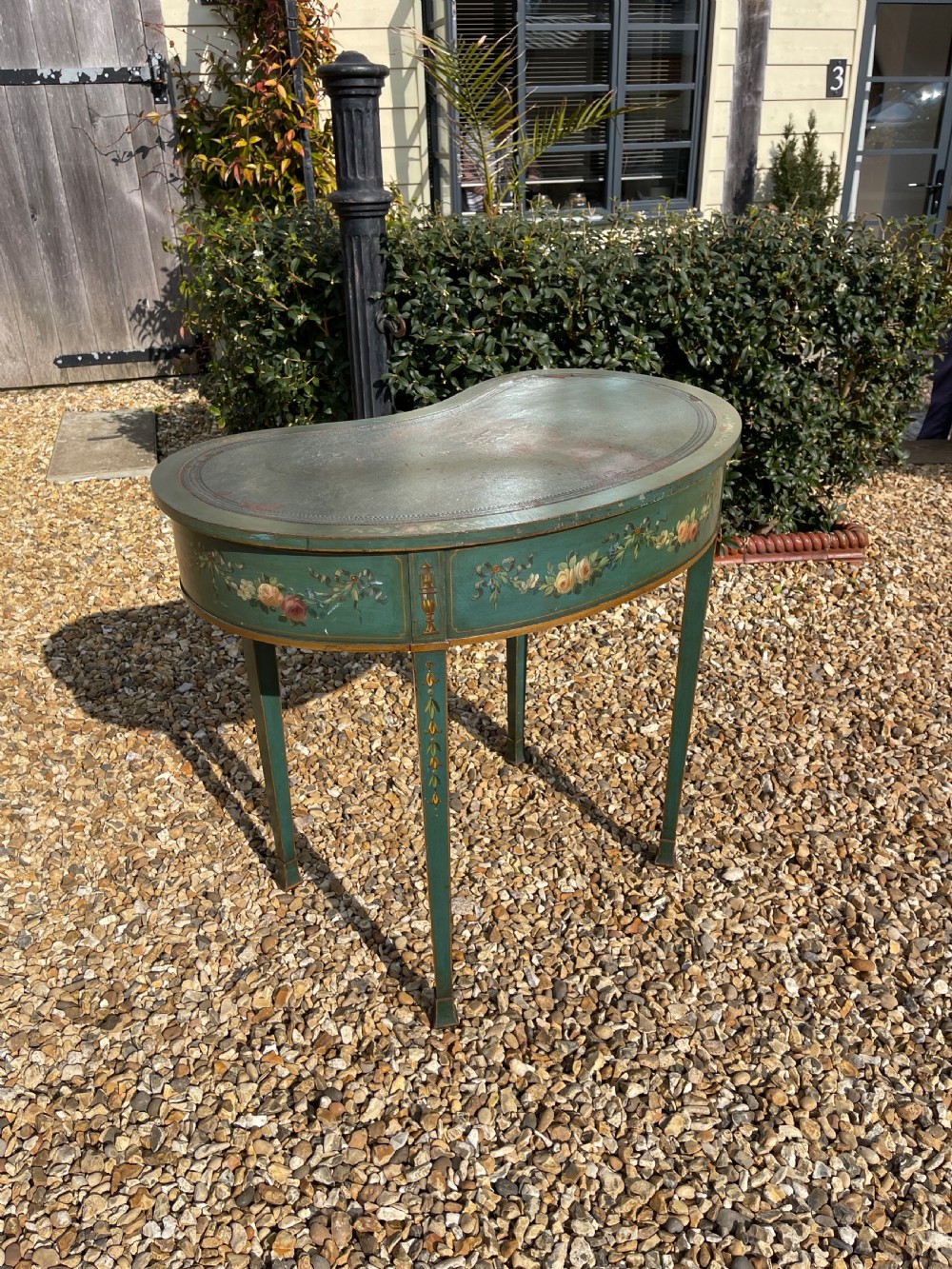 A late Victorian kidney-shaped writing desk finished in green paint with hand-painted floral swags and an inset leather top. View V