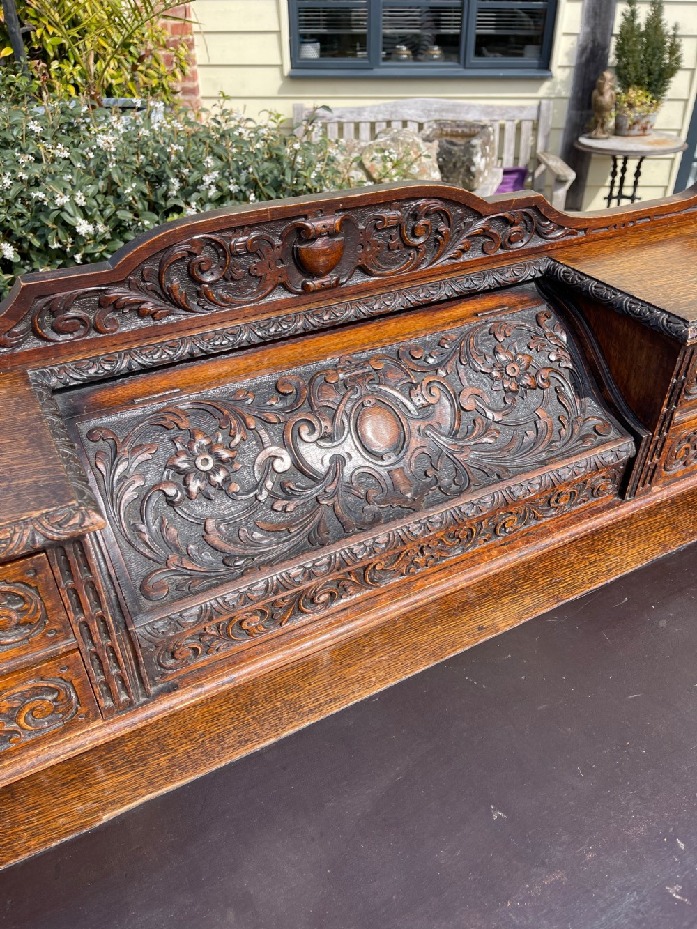 A late Victorian dark oak pedestal desk featuring intricate relief carving across all drawer fronts and a detailed raised superstructure. View II