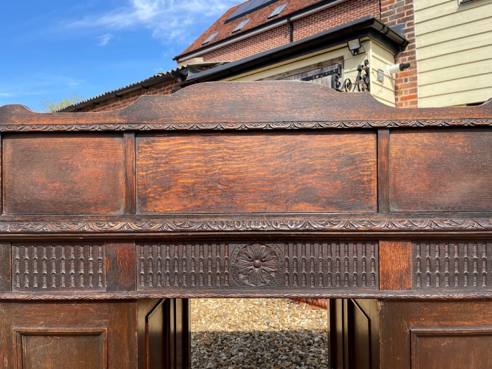 A late Victorian dark oak pedestal desk featuring intricate relief carving across all drawer fronts and a detailed raised superstructure. View VI