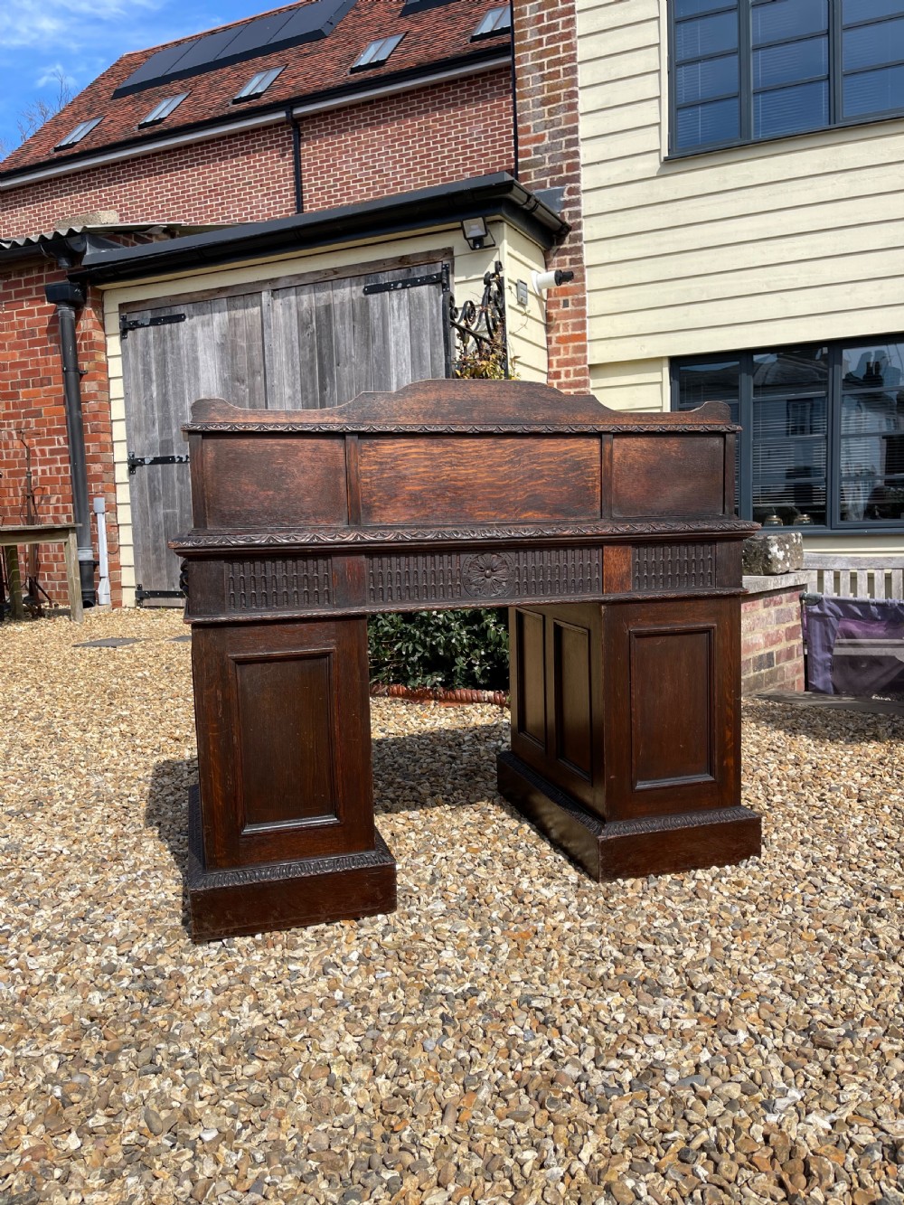 A late Victorian dark oak pedestal desk featuring intricate relief carving across all drawer fronts and a detailed raised superstructure. View VII