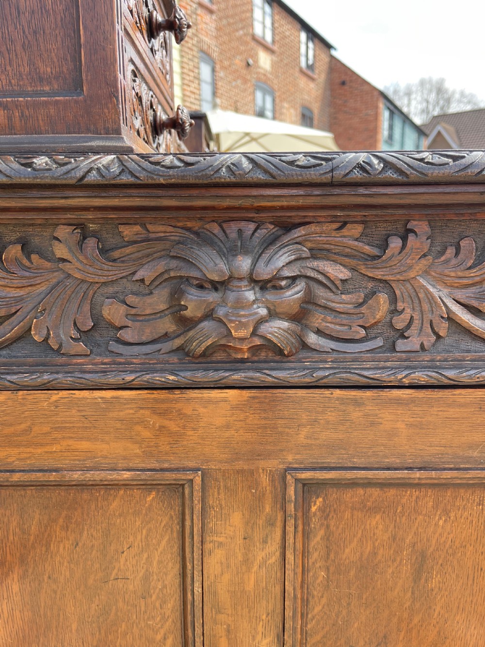 A late Victorian dark oak pedestal desk featuring intricate relief carving across all drawer fronts and a detailed raised superstructure. View XII