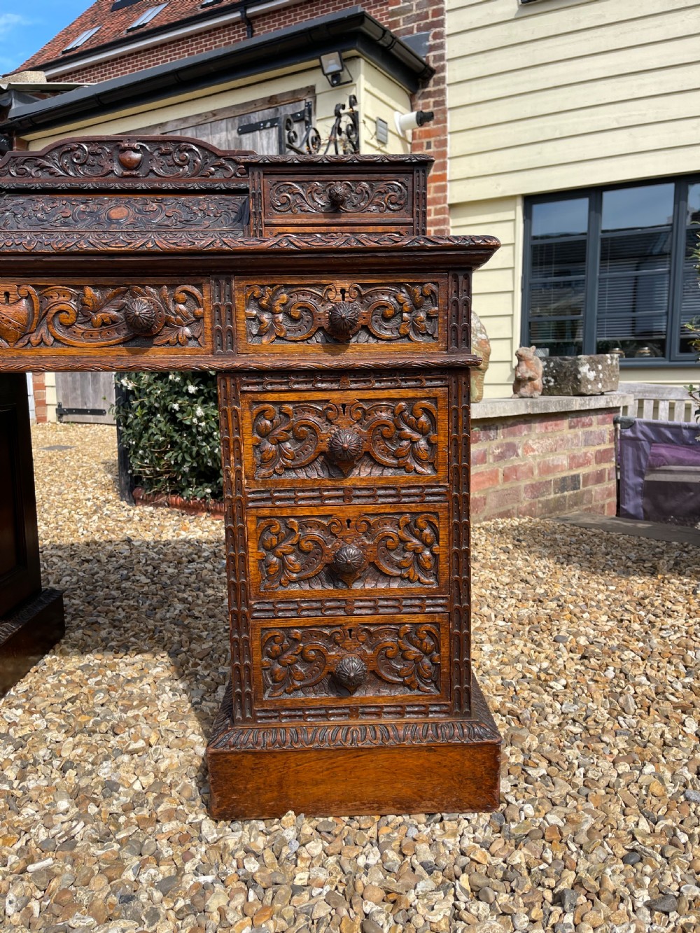 A late Victorian dark oak pedestal desk featuring intricate relief carving across all drawer fronts and a detailed raised superstructure. View XIII