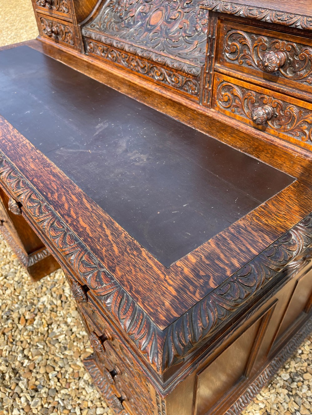 A late Victorian dark oak pedestal desk featuring intricate relief carving across all drawer fronts and a detailed raised superstructure. View XIV